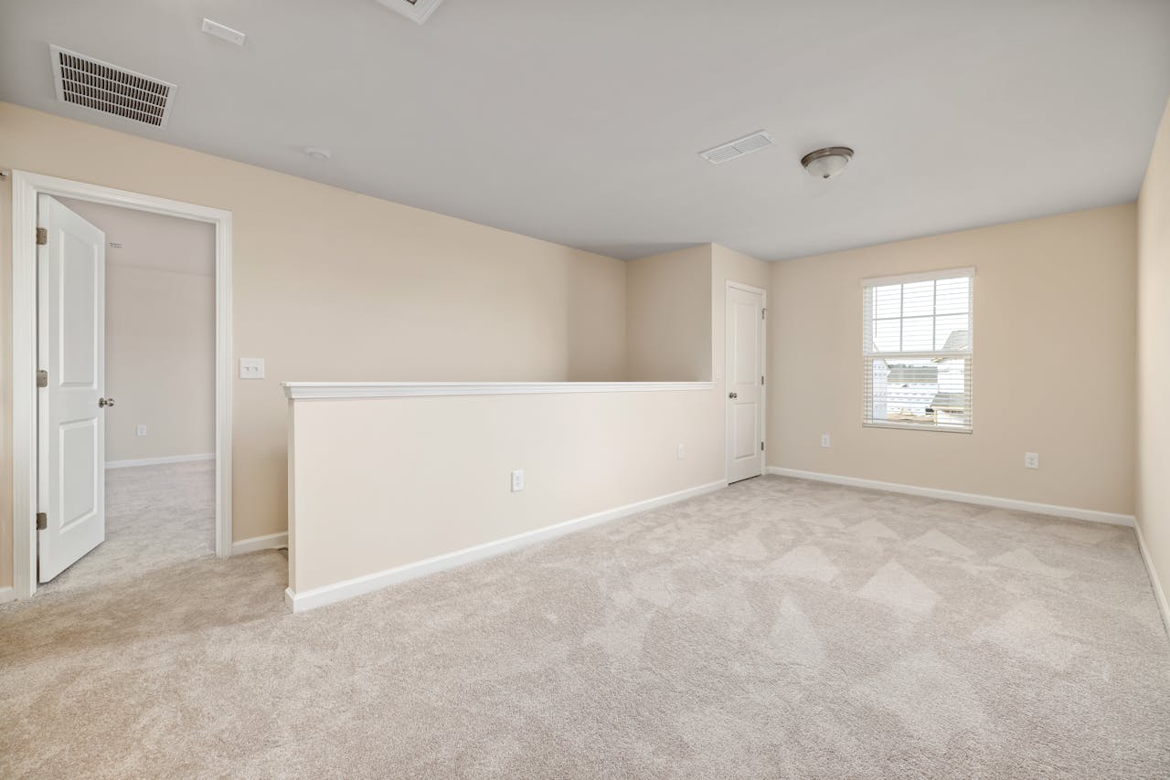 A bright, empty room with beige walls and carpet, ready for interior design ideas.
